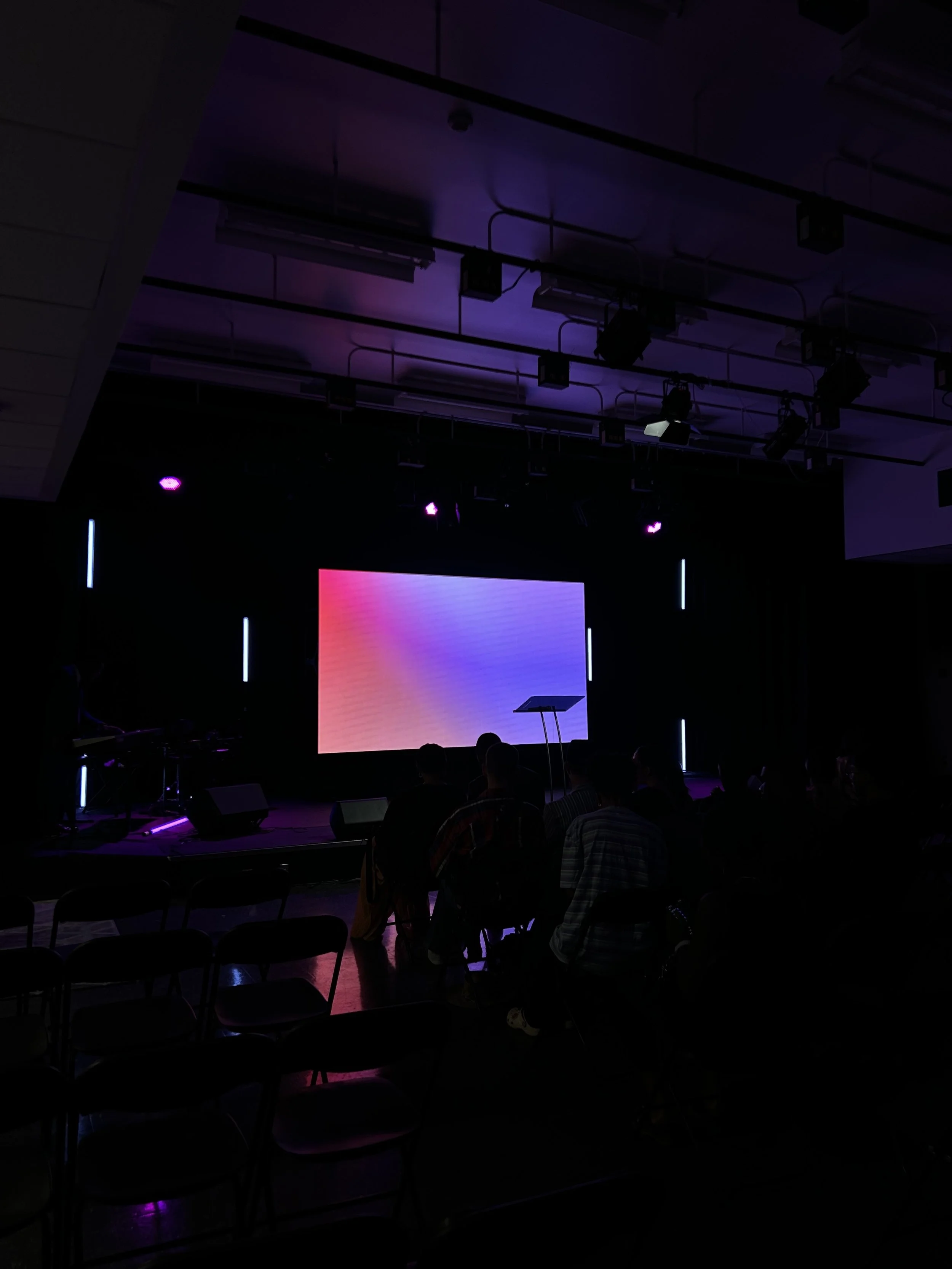 Iridescent pink and blue LED wall glowing on stage in an Ottawa auditorium — bright, crystal-clear content in a dark room
