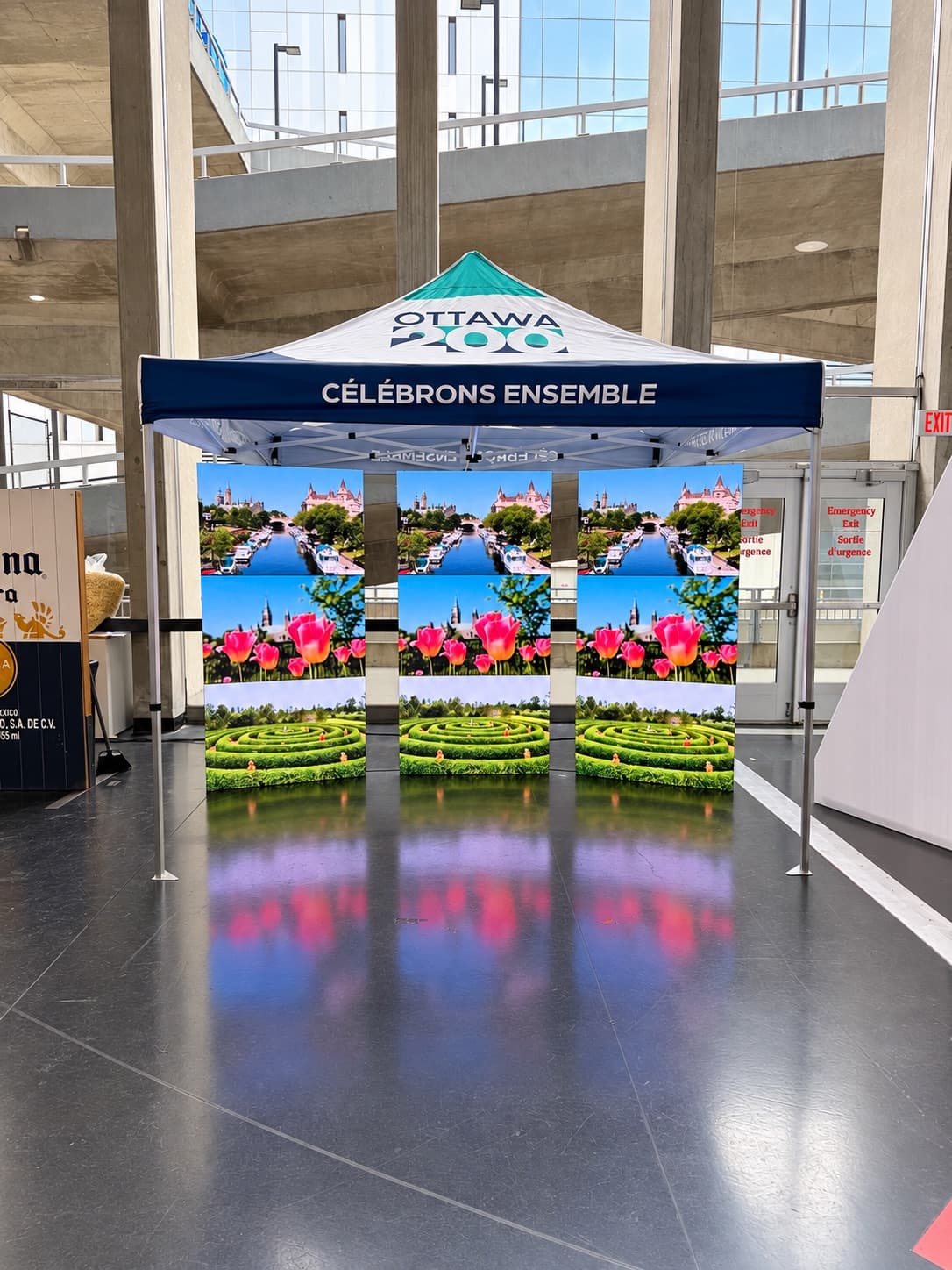 Three freestanding LED poster displays under an Ottawa 200 event tent showing Ottawa scenery